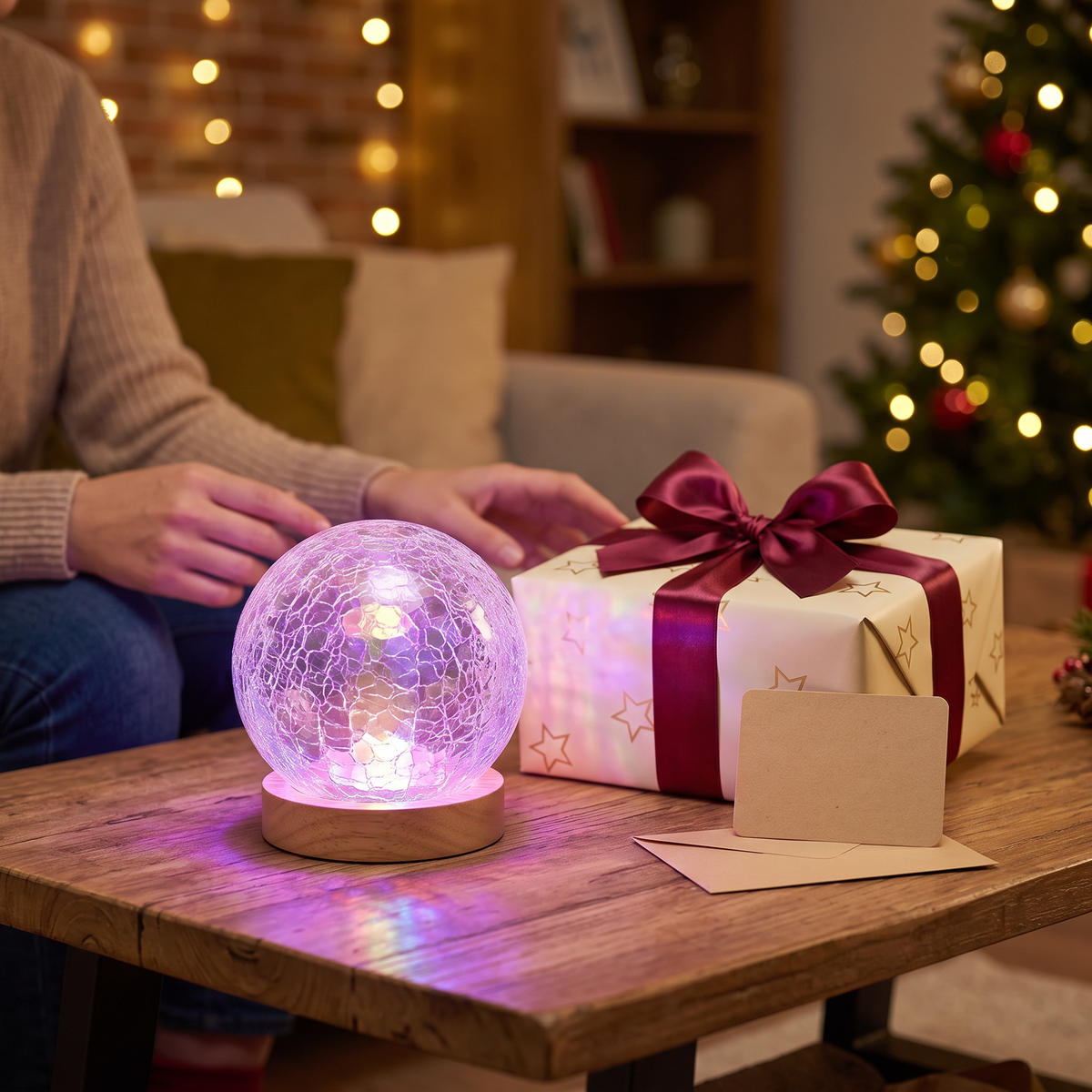Crystal projector lamp on a wooden table beside a wrapped Christmas gift